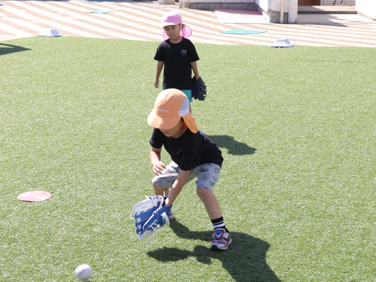 人工芝の会場でグローブを構えてボールを捕る小学生