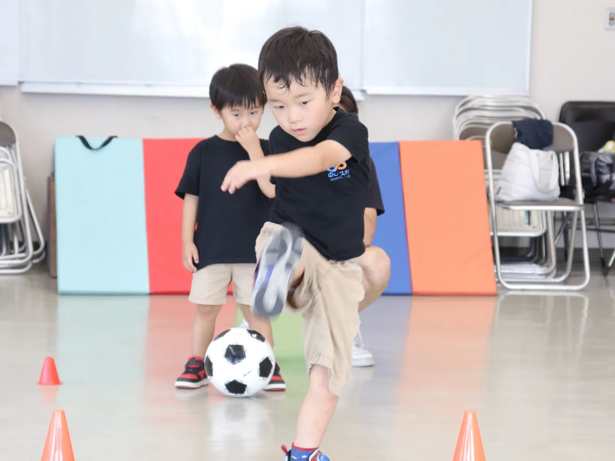 サッカーのドリブル練習をする園児たち